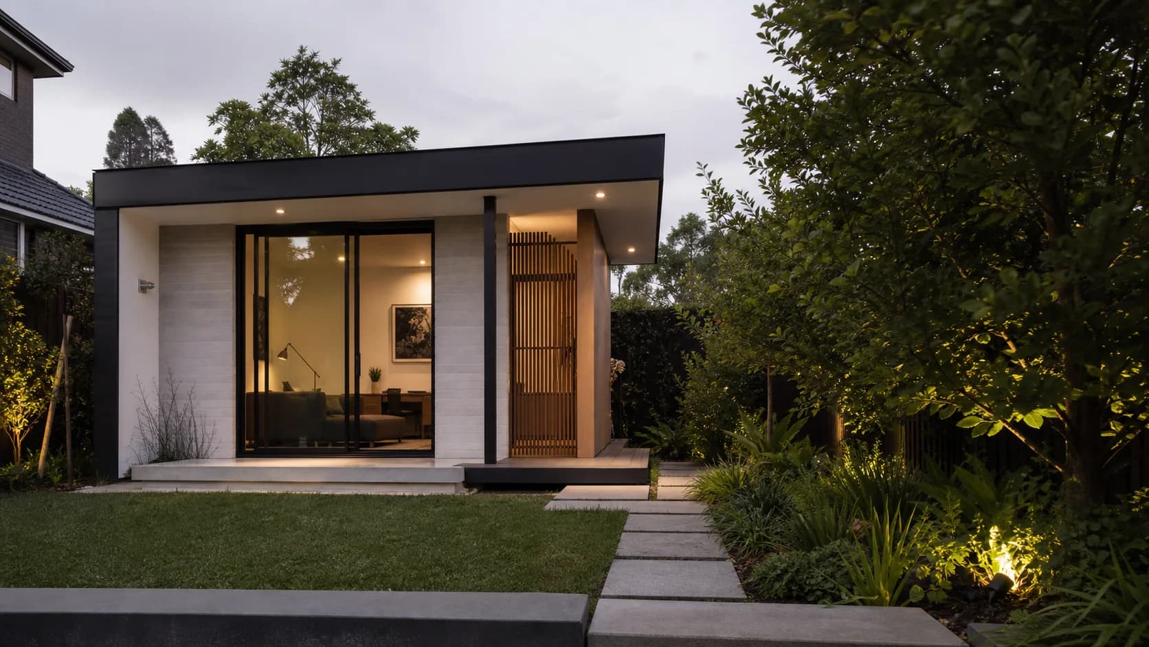Architectural visual of a compact detached studio with masonry walls, black glazing, and a landscaped path
